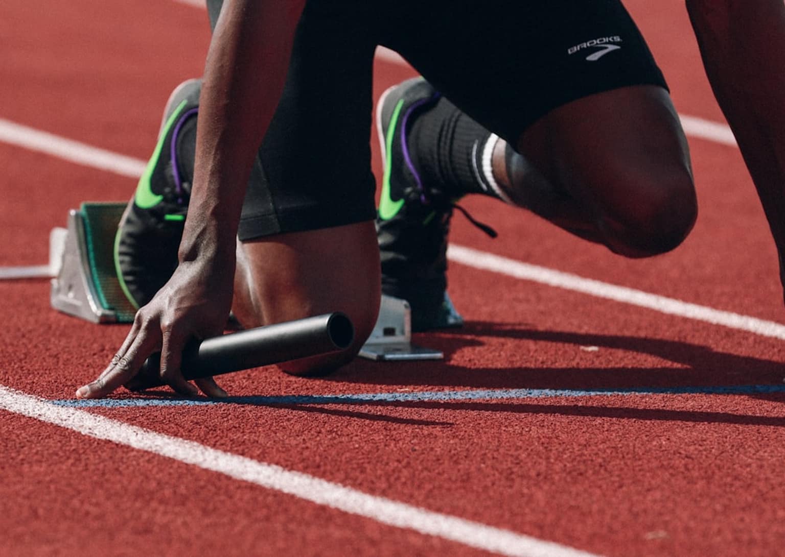 Pistte start pozisyonunda bir sporcunun elleri ve ayakkabıları